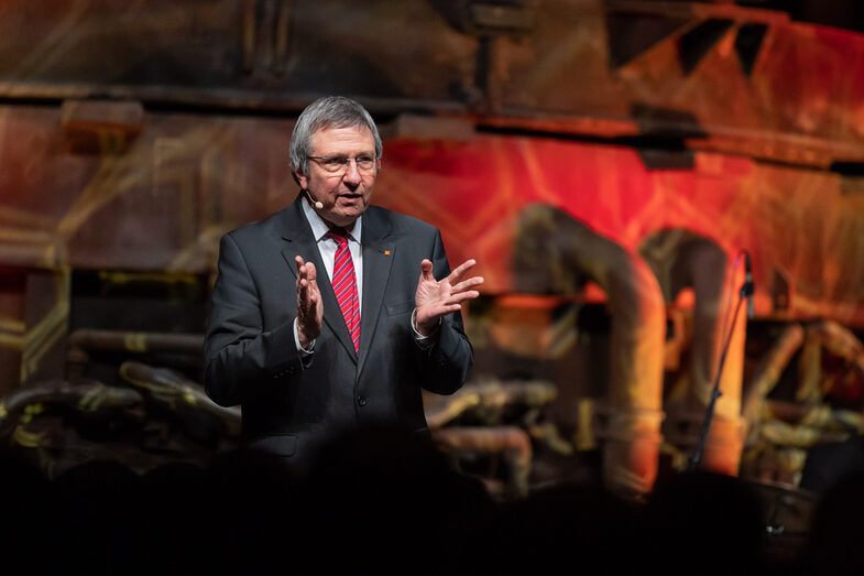 Photo of a male person speaking into a microphone.