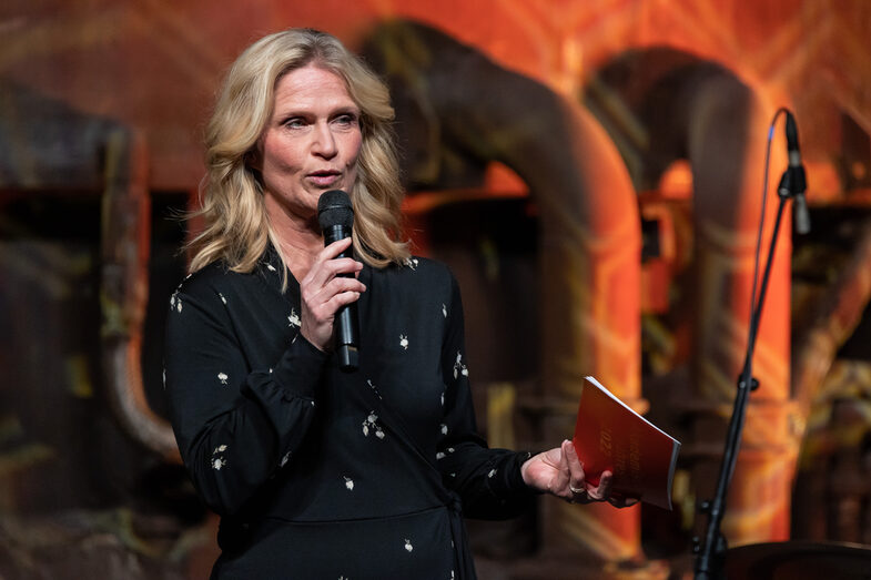 Photo of a female person speaking into a microphone.