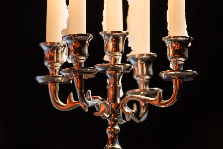 Photo of five burning candles in a candlestick.