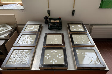 8 augegossene, noch nicht getrocknete Platten auf einem Tisch im Betonlabor