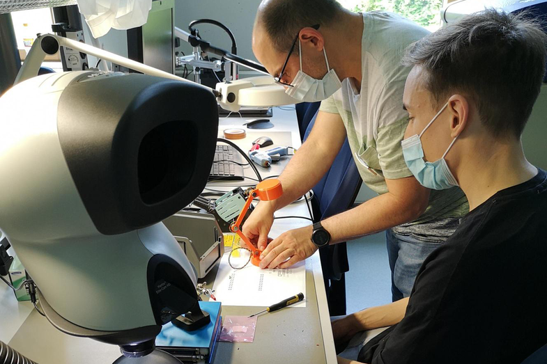 A supervisor shows a participant how to solder during the "Build your smart LED lamp" workshop