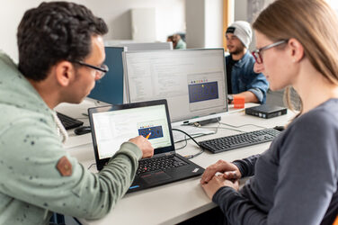 Photo of an employee showing his colleague something on his laptop.