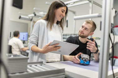 A research assistant explains something to a student about the demonstration product in the lean lab.