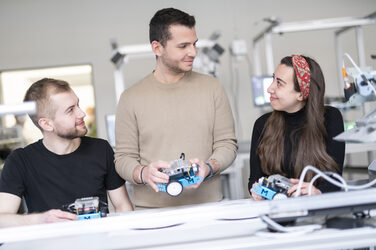 Drei Studierende bearbeiten gemeinsam eine Gruppenaufgabe im Lean Labor.