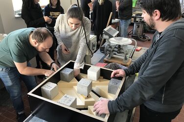 Studierende bereiten im Betonlabor eine quadratische Schalung für ihre Fassadentafel vor.