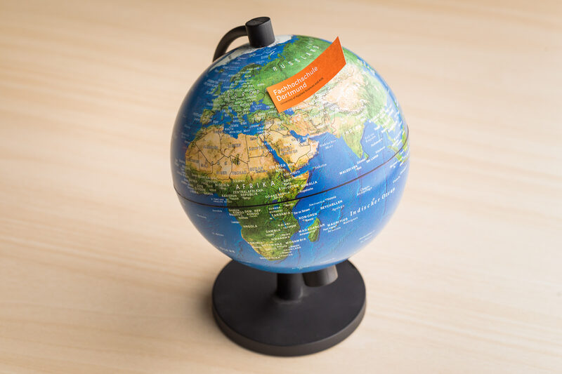 Photo of a globe with a piece of paper with FH word mark stuck to it.