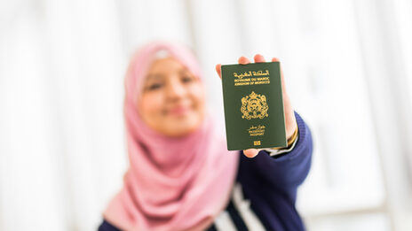 A female student holding her Moroccan passport to the camera.