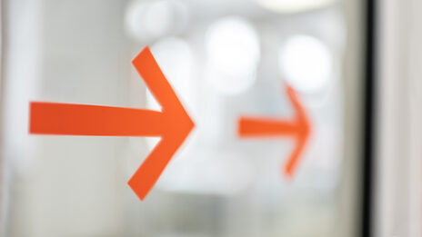 Photo of two orange arrows on a glass door.