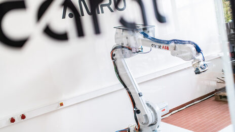 Foto mit Blick durch eine Glasscheibe auf einen Industrieroboter des Projekts AMRU.