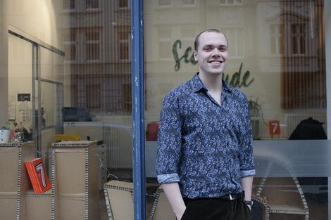 StudyScout Jakob Jung stands outside one of the windows of the Hochschule vor Ort.