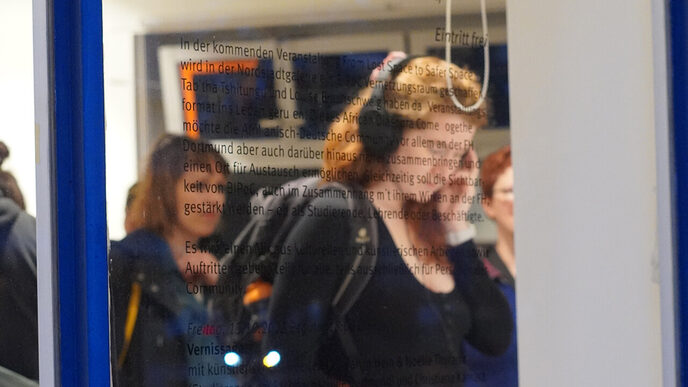 Durchs Fenster kann beobachtet werden, wie eine Person mit Kopfhörern die Ausstellung betrachtet