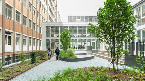 Photo of the inner courtyard at the student workplaces on Sonnenstraße. Two women are walking in the courtyard.