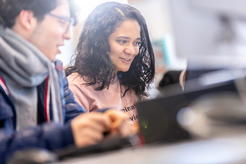 Foto von einer Studentin und einem Studenten, die in einen Laptop schauen.