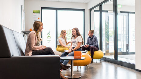 Photo of a waiting room in which several people are sitting and talking __Young people sittin in a waiting room and talking.