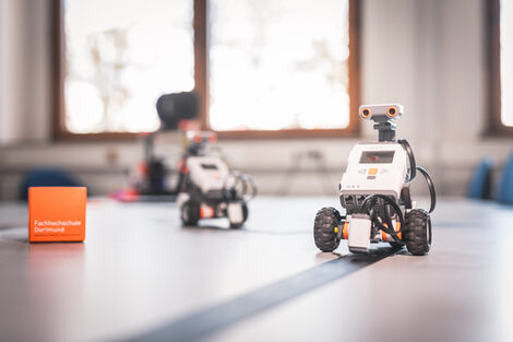 Foto von zwei Lego-Robotern, die eine Spur abfahren. __ <br>Two Lego robots follow the trail.