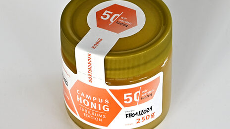 Produktaufnahmen eines Honigglases im Look des Jubiläums-Etikett. Auf dem Etikett seht "Campus Honig - Jubiläums Edition" und es zeigt das Logo 50 Jahre Fachhochschule Dortmund.
