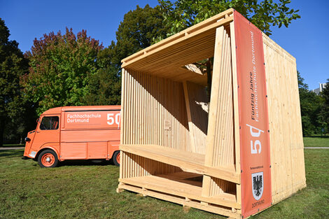 The Fachhochschule Dortmund's wooden seating cube is located in a green area near the Westfalenhallen subway station.