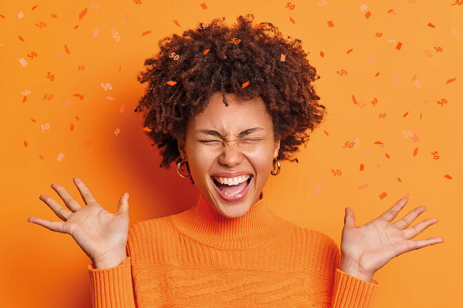 A young female reader cheers and is happy. Confetti with the number 50 trickles around her.