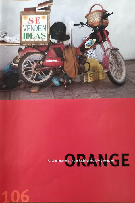 Das Deckblatt der ersten Orange ist zu großen Teilen Rot mit dem schwarzen Schriftzug "Orange" darauf. Oben drüber ist ein alter Rolle und Gerümpel auf einem Foto.