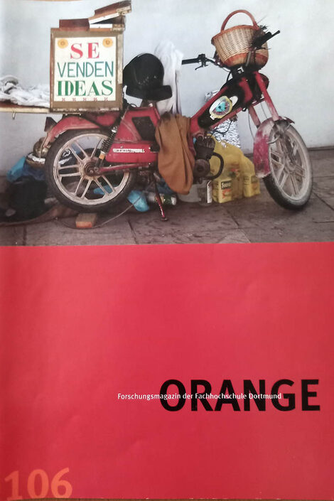 The cover of the first orange is largely red with the black lettering "Orange" on it. Above it is an old roll and junk on a photo.