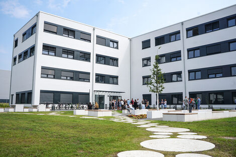 A group of people are standing in front of the white building at Emil-Figge-Straße 38b.