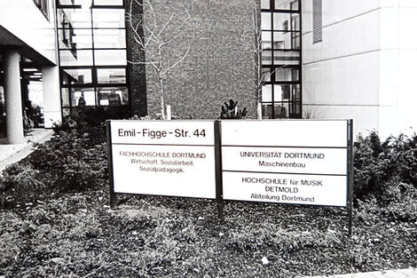 Vor dem Neubau Emil-Figge-Str. 44 steht ein Schild mit der Aufschrift, wer in diesem Gebäude alles untergebracht ist: Die FH Dortmund mit Wirtschaft, Sozialarbeit und Sozialpädagogik, die Universität Dortmund mit Maschinenbau und die Hochschule für Musik Detmold, Abteilung Dortmund.