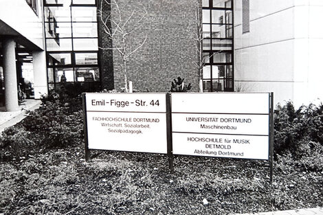 In front of the new building at Emil-Figge-Str. 44, there is a sign showing who is housed in this building: Fachhochschule Dortmund with Business Studies, Social Work and Social Pedagogy, the University of Dortmund with Mechanical Engineering and the Detmold University of Music, Dortmund Department.