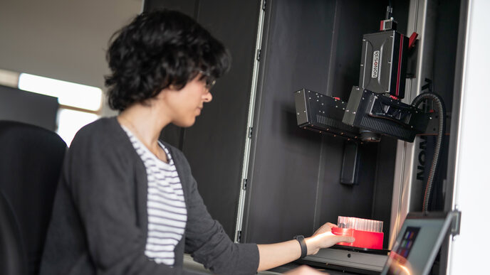 Eine weiblich gelesene Person platziert einen Objektträger unter einer Hyperspektralkamera