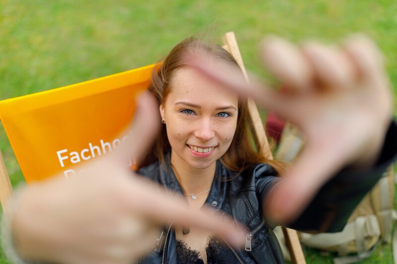 Photo of a student forming a square with her index fingers and thumb in front of her and looking through it.