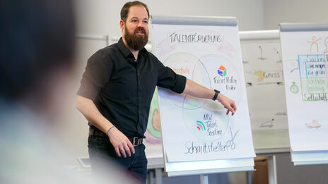 Photo of an employee at a seminar offered by the personnel development department. He is explaining something using a flipchart on which drawings and labels can be seen.__Photo of an employee at a seminar offered by the personnel development department. He is explaining something using a flipchart on which drawings and labels can be seen.