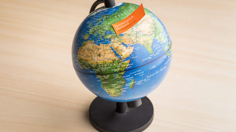 Photo of a globe with a note with the FH word mark stuck to it.