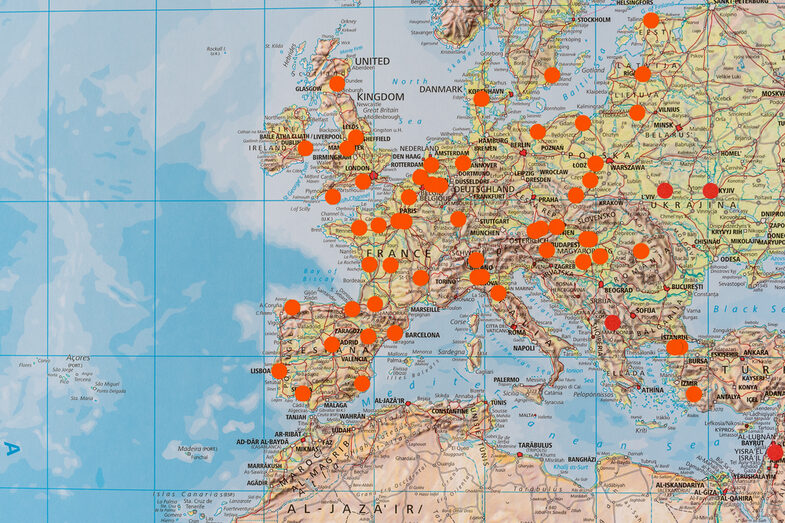 Close-up of a large world map on which places are marked with orange dots.