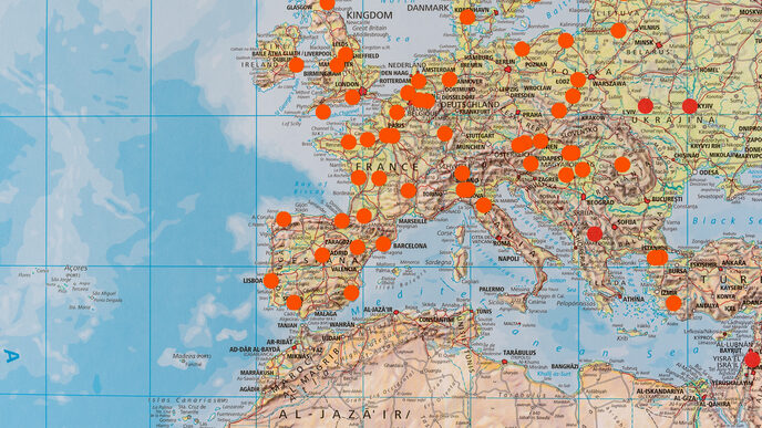 Close-up of a large world map on which places are marked with orange dots.