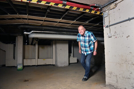 A person walks through a low corridor towards the camera.