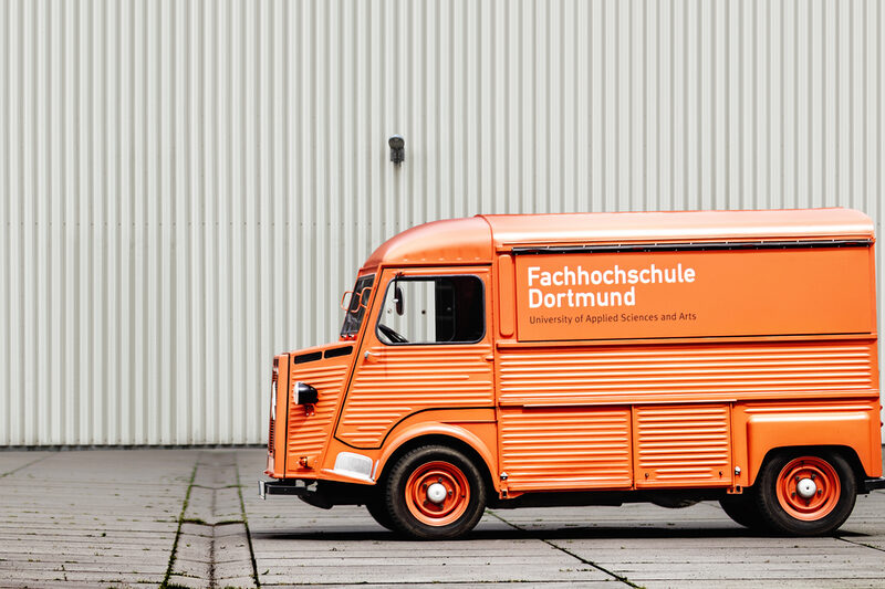 Photo of the Citroen HY in front of a white industrial building. __ Citroen HY in front of a white industrial building.