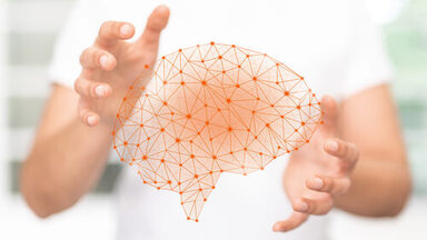 Eine Person hält zwischen ihren Händen eine Grafik eines orangenen Gehirns, das wie ein Netzwerk aufgebaut ist. __ A person holding a virtual orange brain in between her hands, which looks like a network.