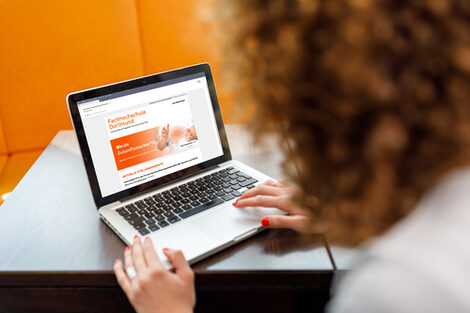 Photo over the shoulder of a female student on a laptop on which the job newsletter of the Fachhochschule Dortmund is called __A female student is sitting on her laptop on which the job newsletter of the Dortmund University of Applied Sciences is called.