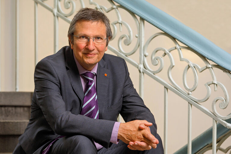 Rector Prof. Dr. Wilhelm Schwick sits on a staircase, his hands folded.