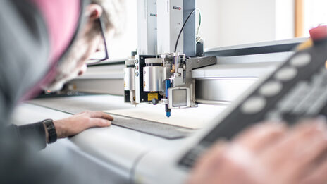 Photo of a man working on the laser cutter and cutting a panel to size.