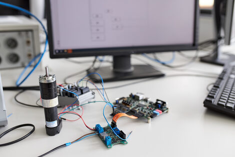 In this workstation, a small motor is controlled and regulated. A PC screen is switched on in the background. A circuit diagram is displayed on the screen.