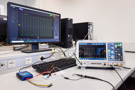 Foto von einer Aufbaute mit Steckbretter zur elektronischen Schaltung und Messgeräten sowie Angaben der Messung auf dem Computer.