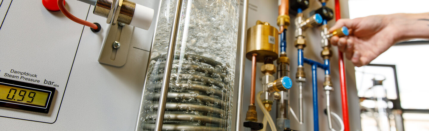 Foto eines Versuchsaufbaus im Labor für Energietechnik und Wärmeübertragung, unter anderem bestehend aus einer Glassäule, in der Wasser erhitzt wird.