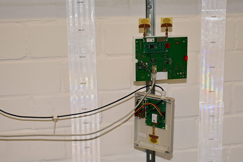 A circuit board mounted in a box on the wall, with strips of reflectors to the right and left of it __A circuit board mounted in a box on the wall, with strips of reflectors to the right and left of it