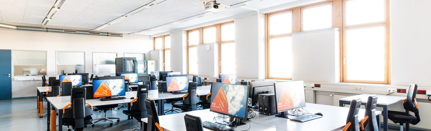 Room shot of the laboratory for networks and operating systems, with several rows or groups of tables equipped with computers.