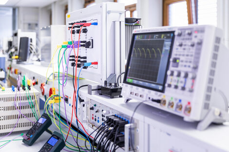Foto aus dem Labor für Leistungselektronik und Antriebssysteme. Zu sehen sind verschiedene Messgeräte und Computer mit vielen farbigen Kabeln.