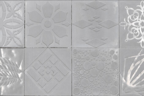 12 quadratische Ornamentplatten aus Beton zusammengestellt in zwei Reihen