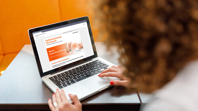 Photo over the shoulder of a female student on a laptop on which the job newsletter of the Fachhochschule Dortmund is called __A female student is sitting on her laptop on which the job newsletter of the Dortmund University of Applied Sciences is called.