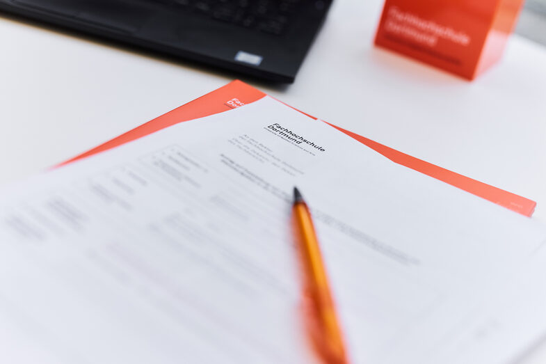 Photo of documents with the caption "Fachhochschule Dortmund" and a ballpoint pen on a table.