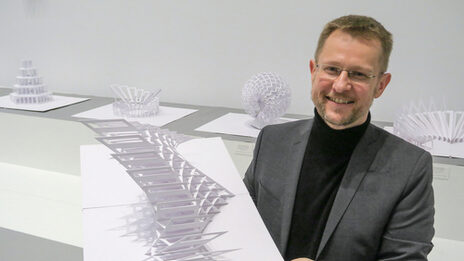 Portrait of Peter Dahmen. He is holding a sculpture in his hand.