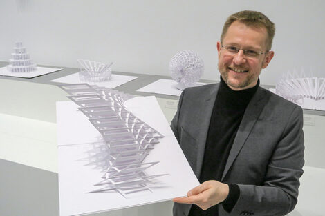 Portrait of Peter Dahmen. He is holding a sculpture in his hand.